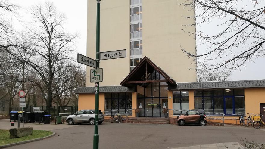 Auf dem Foto ist der Haupteingang der Josephinen-Wohnanlage abgebildet. Davor ist das Straßenschild mit der Aufschrift Burgstraße zu sehen.