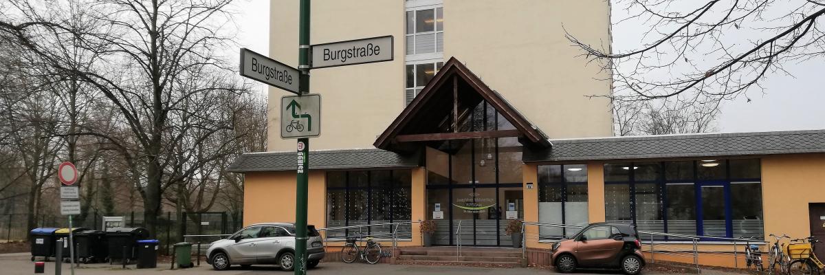 Auf dem Foto ist der Haupteingang der Josephinen-Wohnanlage abgebildet. Davor ist das Straßenschild mit der Aufschrift Burgstraße zu sehen.